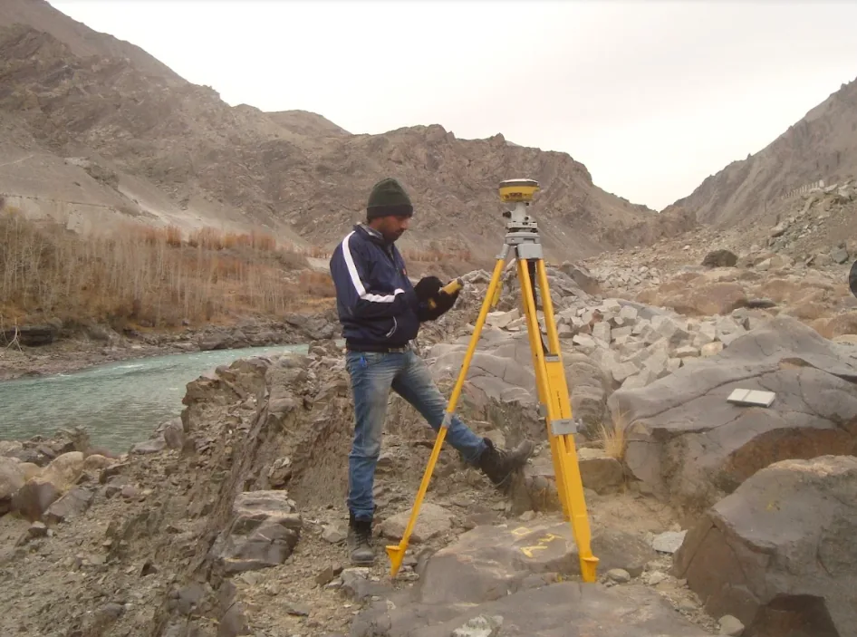 NKMPV surveyor with DGPS RTK rover and field controller on rocky high-altitude Himalayan terrain.
