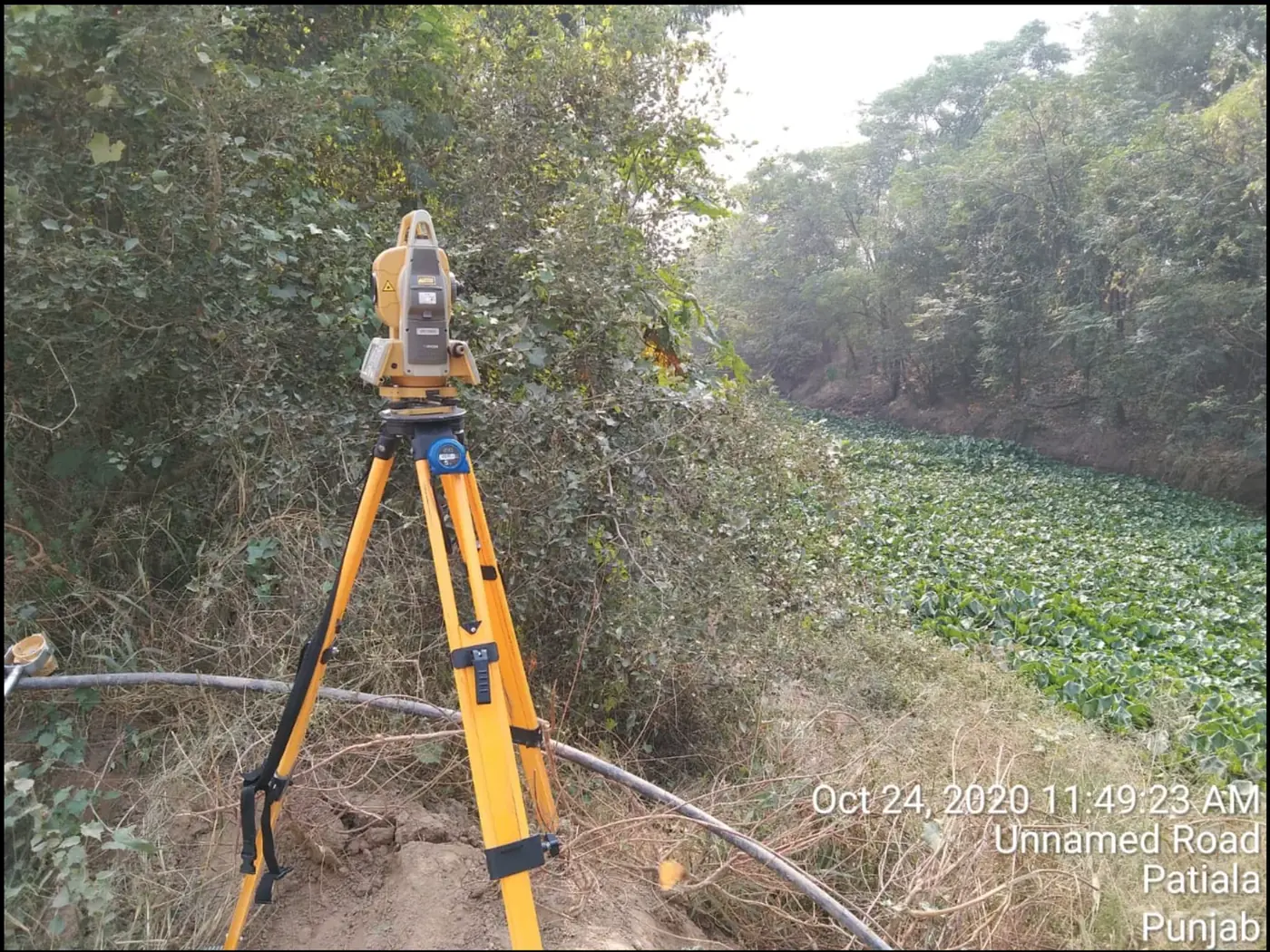 NKMPV Topcon total station setup near canal vegetation in Patiala, Punjab.